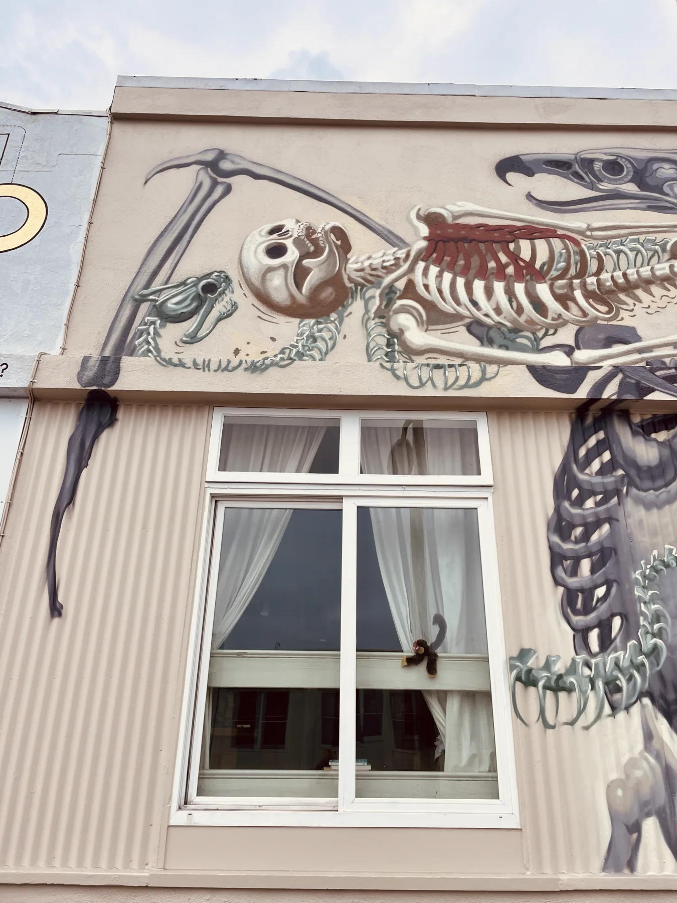 Close view of the Nychos mural above a window: a skeletal animal in his exploded-anatomy style